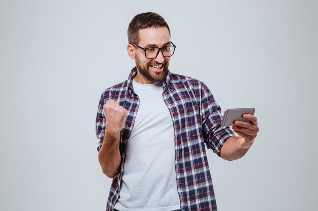 Hombre barbudo feliz en eyeglases mirando el teléfono