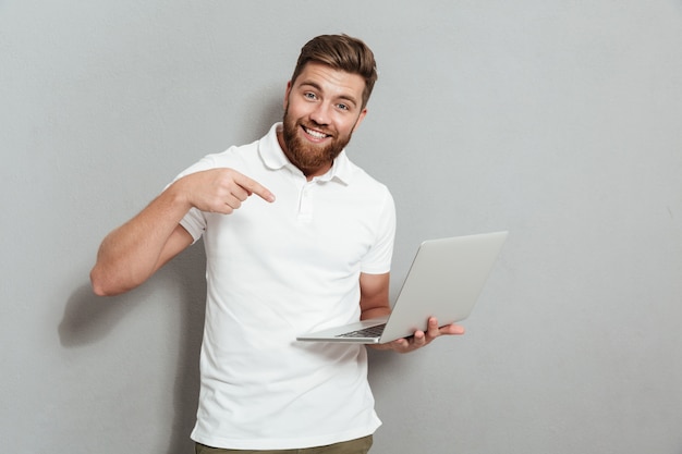 Hombre barbudo feliz que sostiene una computadora portátil