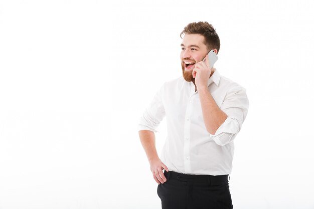 Hombre barbudo feliz en ropa de negocios hablando por teléfono inteligente