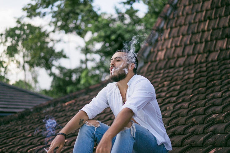 Foto gratuito hombre barbudo fumando en el techo