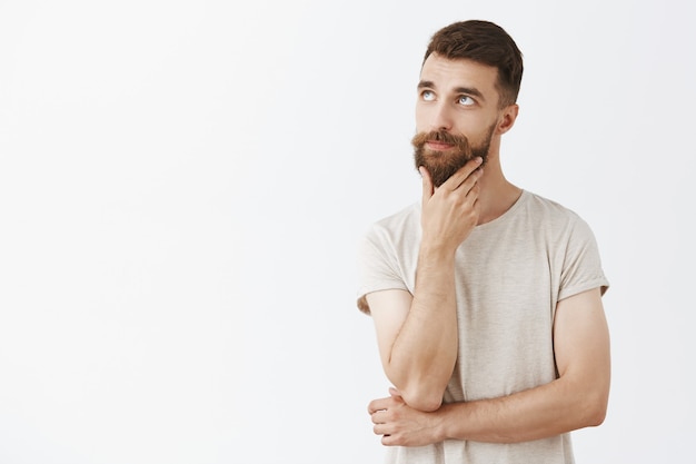 Foto gratuita hombre barbudo guapo descarado posando contra la pared blanca