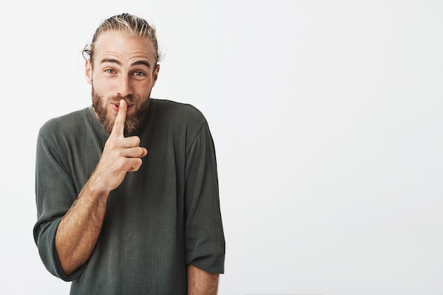 Foto gratuita hombre barbudo guapo divertido haciendo silencio gesto con la mano pidiendo silencio