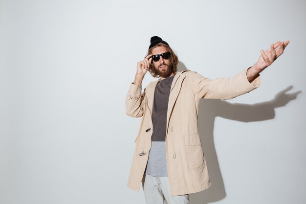 Hombre barbudo hipster con gafas de sol de pie aislado