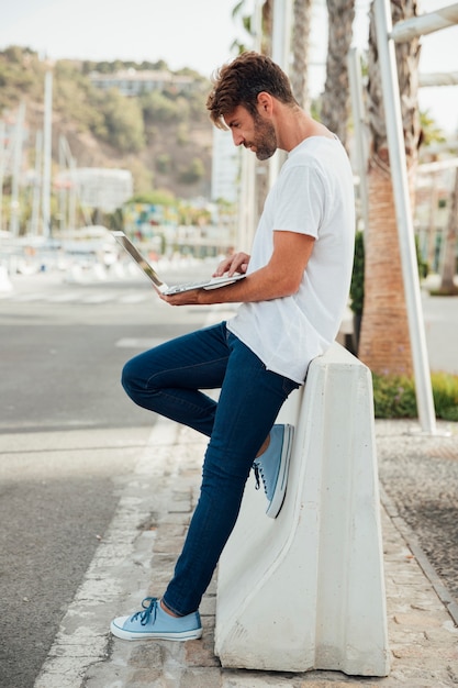 Foto gratuita hombre barbudo con jeans sosteniendo un cuaderno