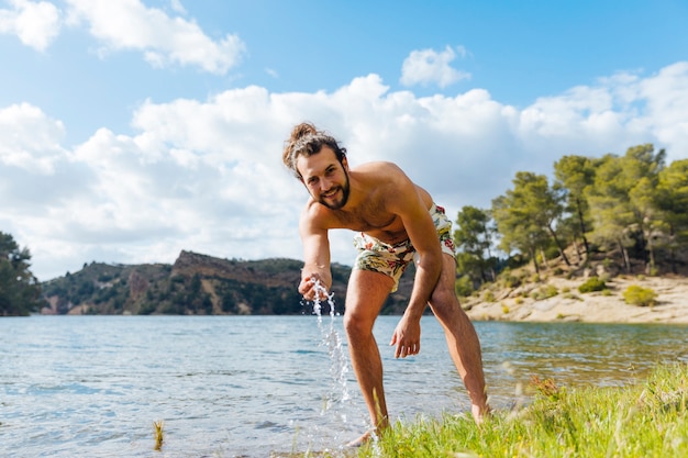 Foto gratuita hombre barbudo joven que descansa sobre el lago