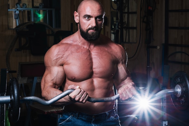 El Hombre Musculoso Posa En El Gimnasio Con Un Cinturón Atlético. Deportes,  Culturismo, Concepto De Levantamiento De Pesas. Técnica Mixta Fotos,  retratos, imágenes y fotografía de archivo libres de derecho. Image  161739753