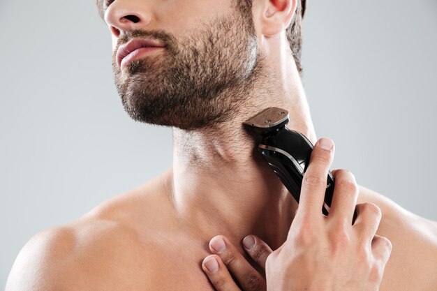 Hombre barbudo con maquinilla de afeitar eléctrica