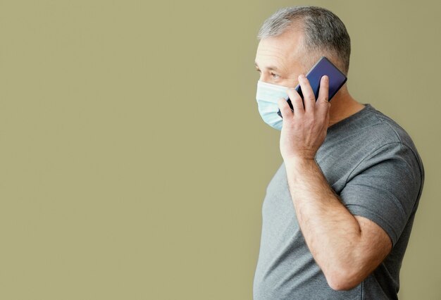 Hombre barbudo con mascarilla quirúrgica con teléfono