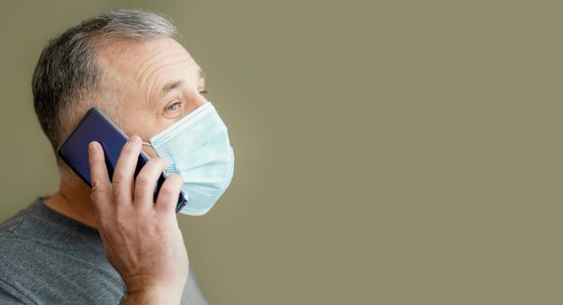 Hombre barbudo con mascarilla quirúrgica con teléfono