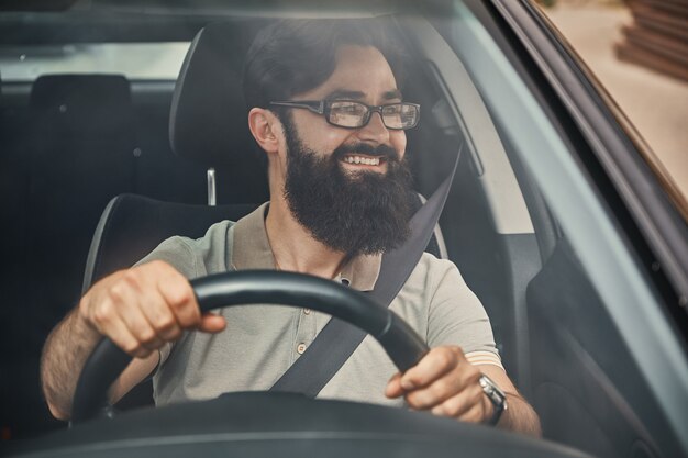 Un hombre barbudo moderno conduciendo un automóvil