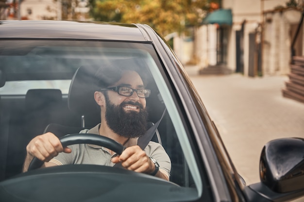 Un hombre barbudo moderno conduciendo un automóvil