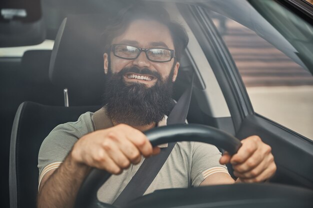 Un hombre barbudo moderno conduciendo un automóvil