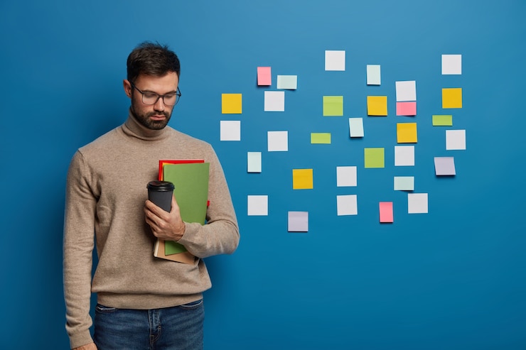 Foto gratuito hombre barbudo organizando sus tareas usando notas adhesivas