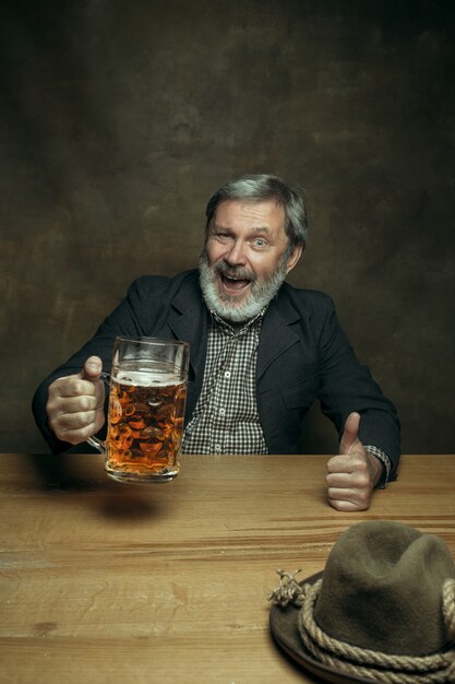 Hombre barbudo sonriente bebiendo cerveza en pub