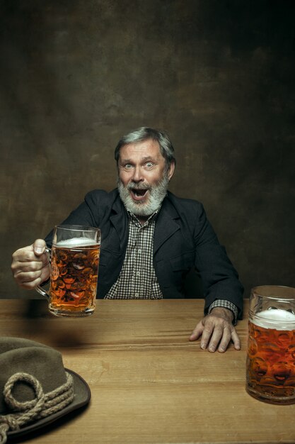 Hombre barbudo sonriente bebiendo cerveza en pub