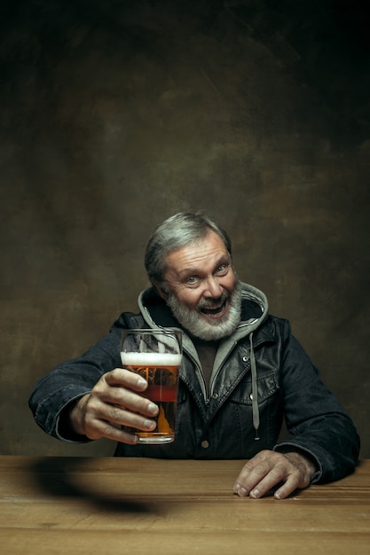 Hombre barbudo sonriente bebiendo cerveza en pub