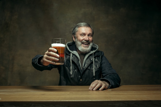 Hombre barbudo sonriente bebiendo cerveza en pub