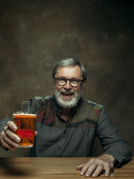 Hombre barbudo sonriente bebiendo cerveza en pub