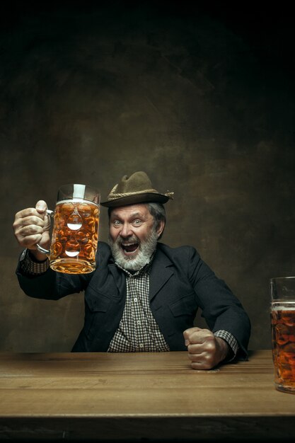 Hombre barbudo sonriente bebiendo cerveza en pub