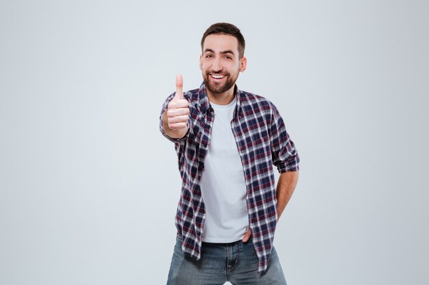 Hombre barbudo sonriente en camisa mostrando el pulgar hacia arriba en