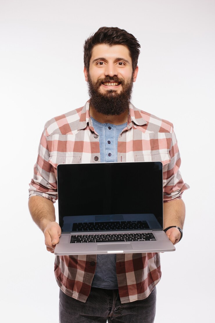 Foto gratuito hombre barbudo sonriente feliz que sostiene la computadora portátil de la pantalla en blanco aislada sobre la pared blanca