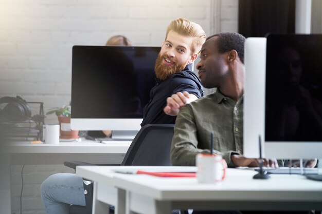 Hombre barbudo sonriente que llama la atención de su colega masculino