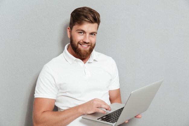 Hombre barbudo sonriente que usa la computadora portátil