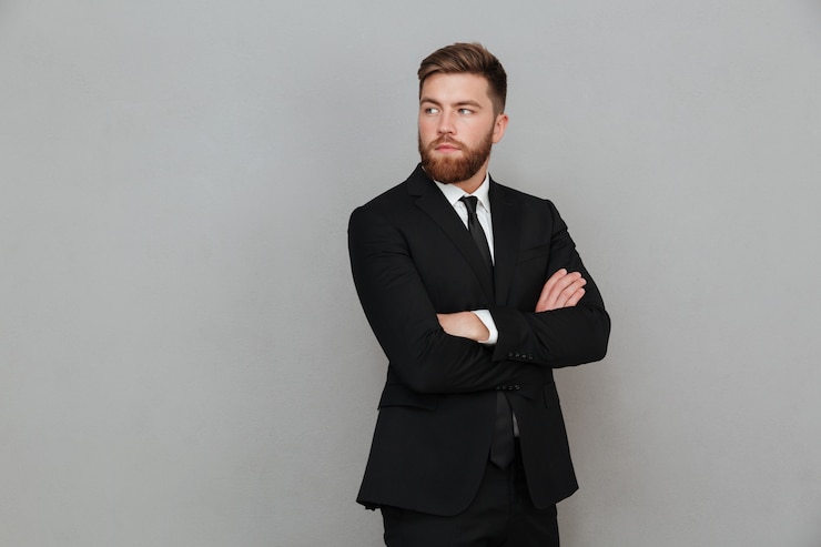 Foto gratuito hombre barbudo en traje posando con los brazos cruzados