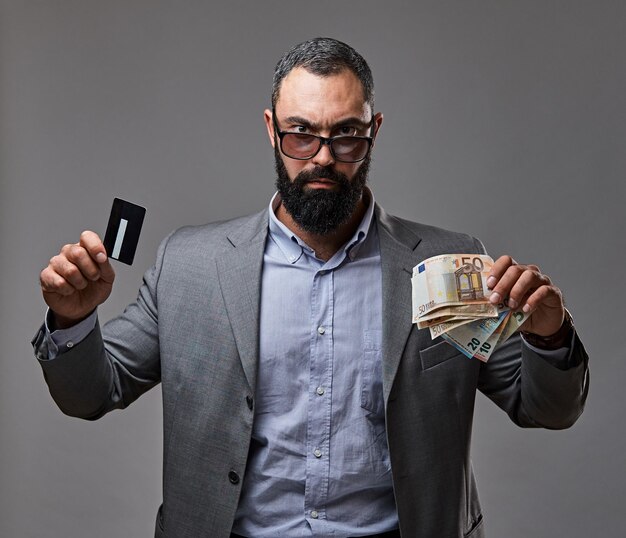 Un hombre barbudo vestido con un traje atrapa billetes de dinero en el aire.