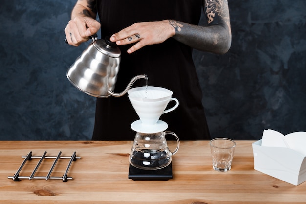 Hombre barista elaborando café. Método alternativo verter más.