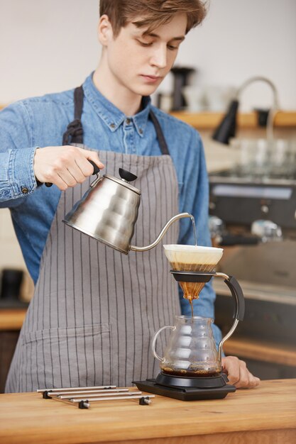 Hombre barista vertiendo agua a través de terrenos haciendo café pouron.