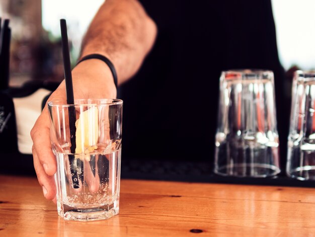 Hombre barman sirviendo vaso de bebida clara