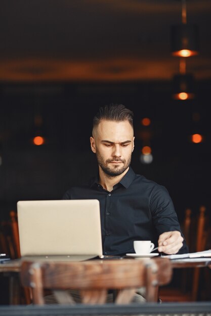 El hombre bebe café. El hombre de negocios lee documentos. Director con camiseta.