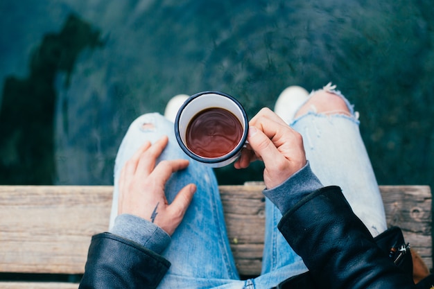 El hombre bebe café de la taza de esmalte al aire libre