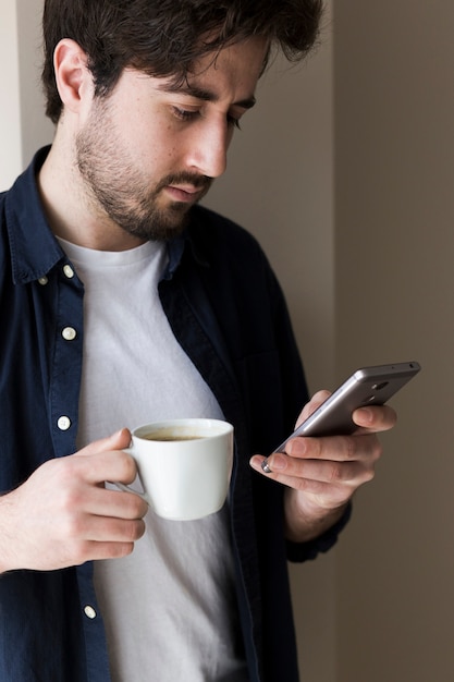 Hombre con bebida usando smarphone