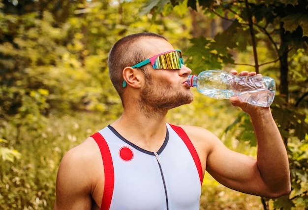 Hombre bebiendo agua en el bosque de verano.