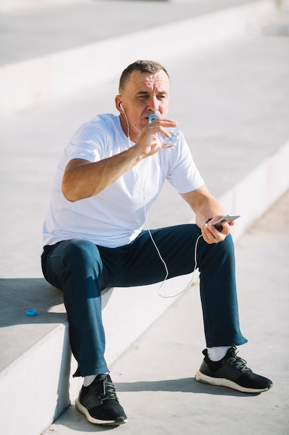 Hombre bebiendo agua de botella de plástico