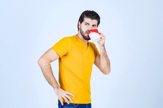 Hombre bebiendo café de su taza roja.