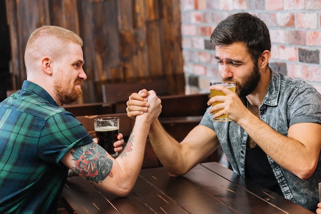 Foto gratuita hombre bebiendo cerveza mientras lucha con su amigo