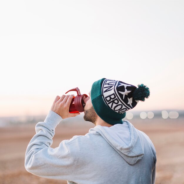 Hombre bebiendo del termo en la naturaleza