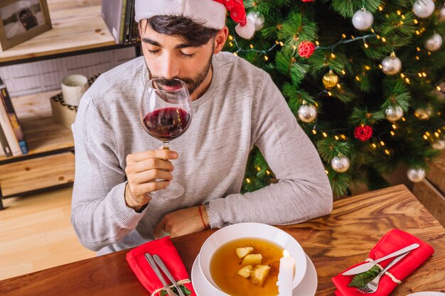 Hombre bebiendo de vaso de vino en navidad