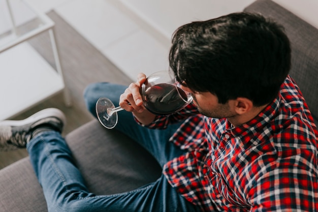 Hombre bebiendo vino en el sofá