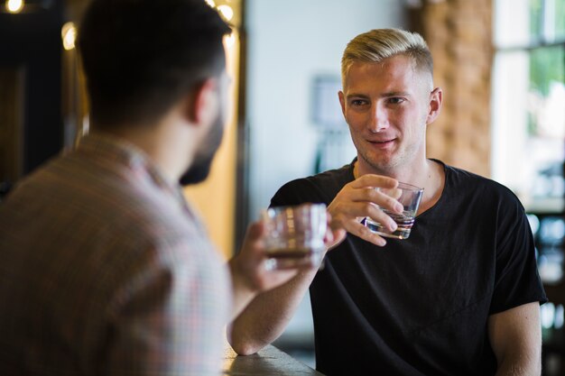 Foto gratuita hombre bebiendo whisky con su amigo en el bar