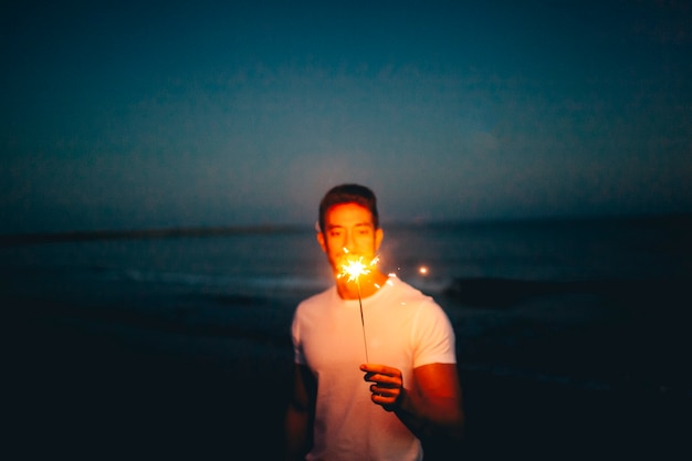 Hombre con bengala en una playa de noche