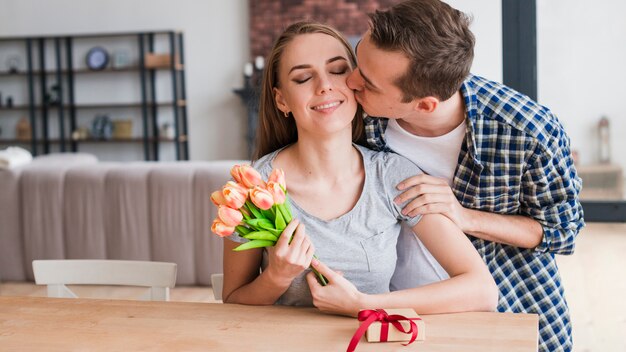 Hombre besando feliz esposa y dando regalos