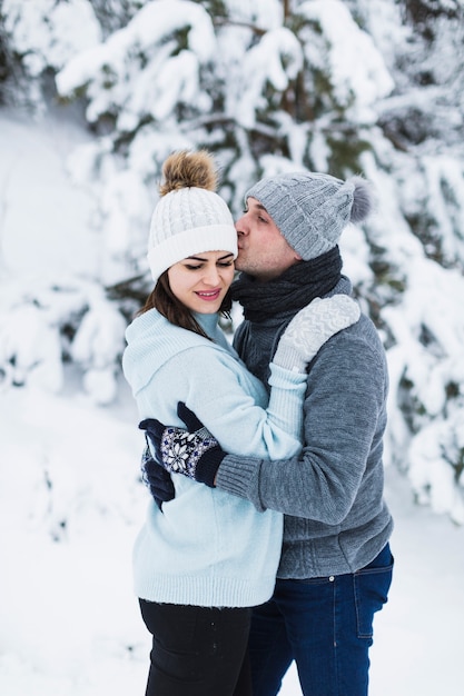 Foto gratuita hombre besando a mujer en bosque de invierno