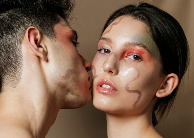 Foto gratuita hombre besando a mujer en la mejilla con caras pintadas