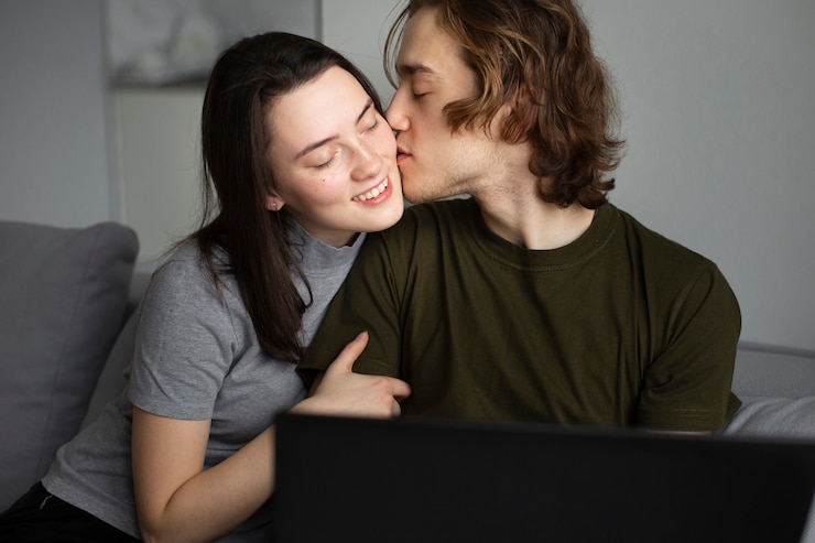 Foto gratuito hombre besando a la novia mientras trabajaba en la computadora portátil