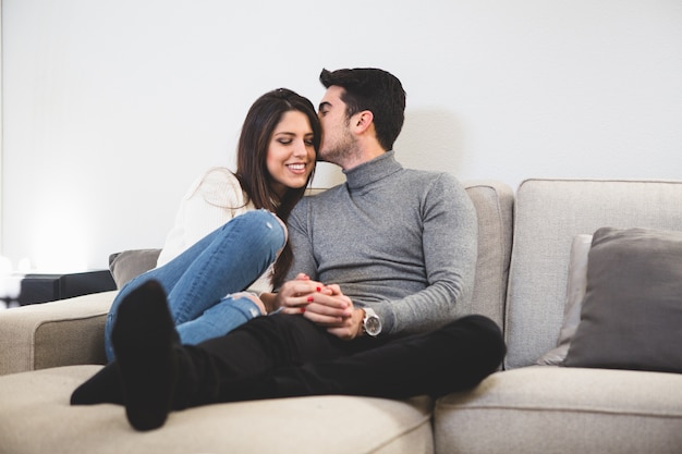 Hombre besándo a su pareja en un sofá