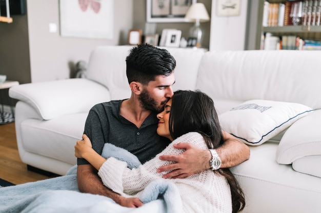 Foto gratuita hombre besándose en la frente de su novia sentado frente al sofá